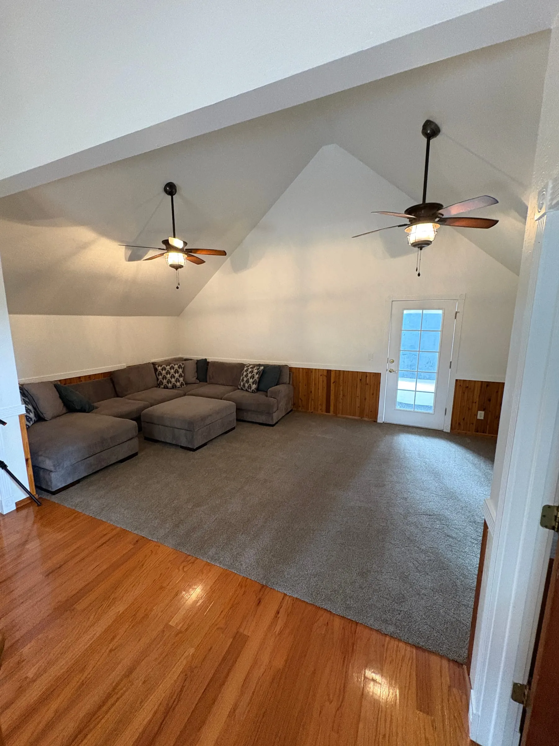 The upstairs landing — a sofa and armchairs on an open carpeted area under a vaulted wood ceiling, with the upstairs bedrooms opening onto it.