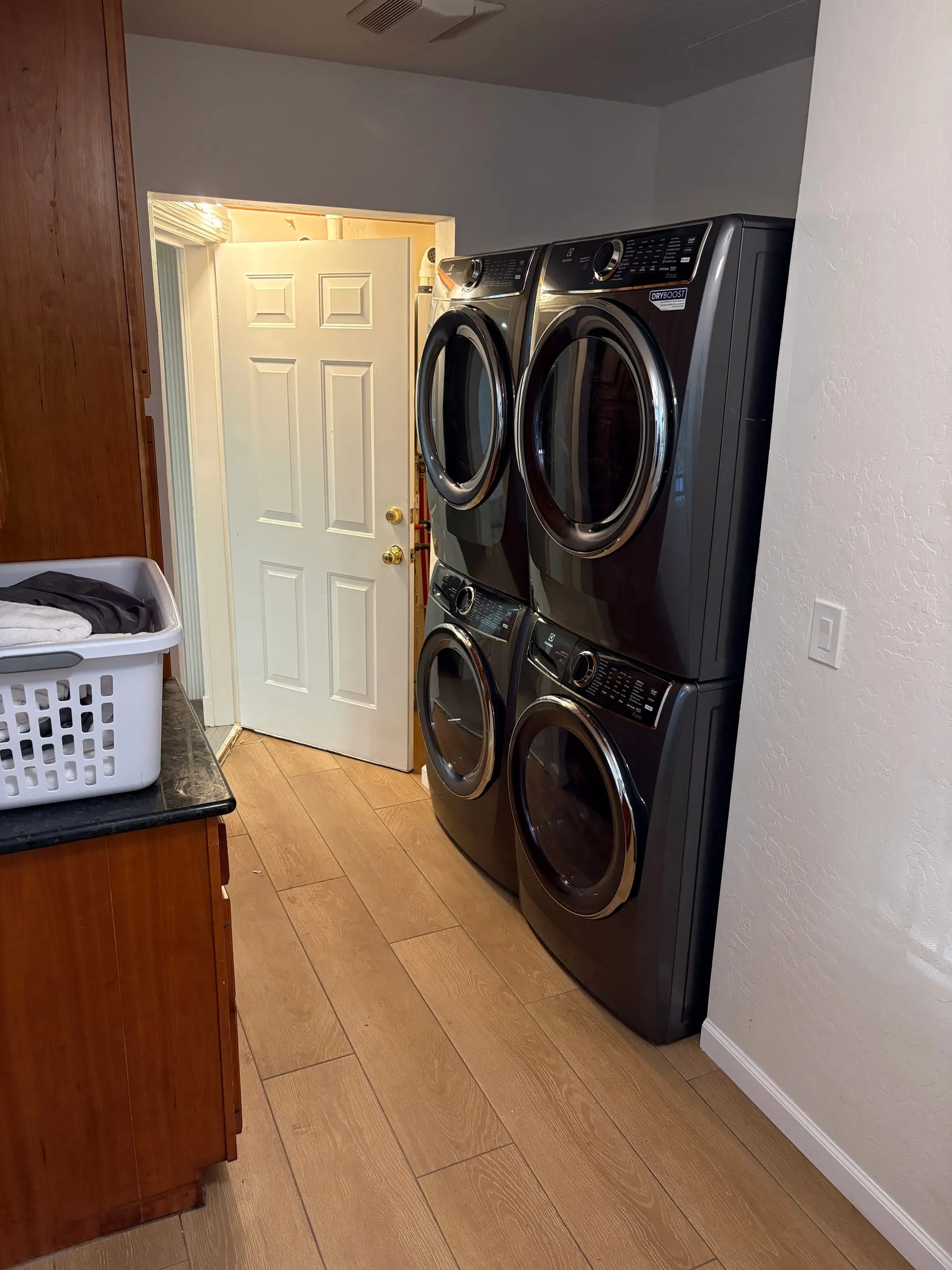 The laundry room — two washers and two dryers in a double-stacked pair, with a laundry basket beside them.