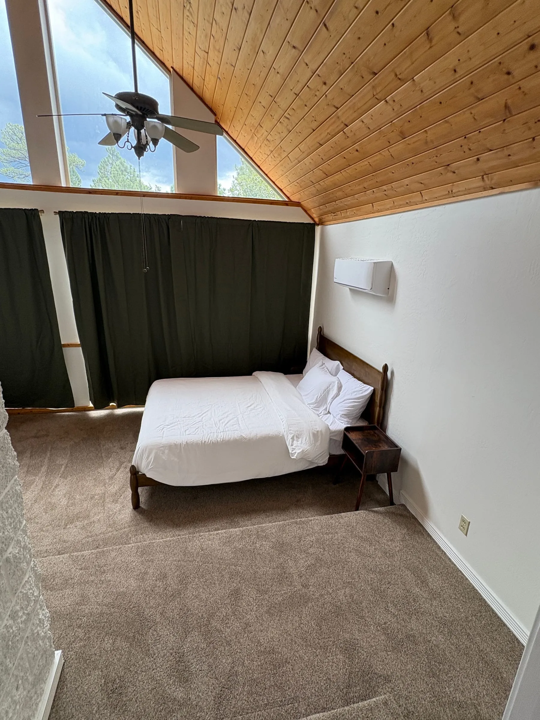 The Window Room from the doorway. A wall-mounted mini-split unit gives the room its own heating and cooling, and the windows have light-blocking curtains with tinted glass above them.